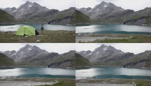 无人机飞过徒步者双臂张开，周围是风景优美的山湖景观高清在线视频素材下载