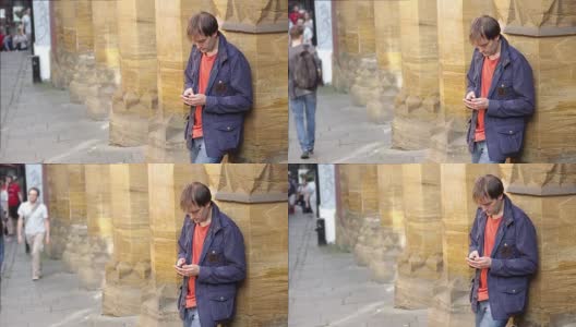 一名年轻人站在人行道上用智能手机输入信息高清在线视频素材下载