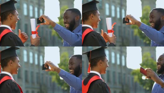 快乐的美国黑人男子拍照的儿子在法官的西装持有文凭高清在线视频素材下载