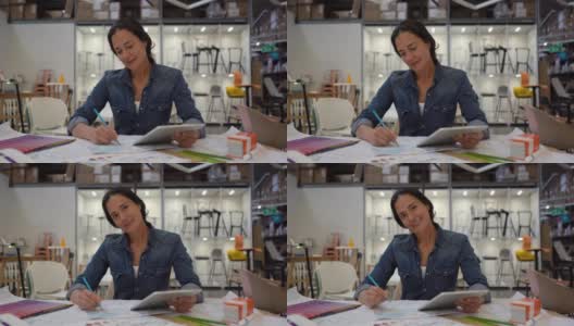 拉丁美洲室内设计师正在用平板电脑画草图，然后面带微笑地面对镜头高清在线视频素材下载