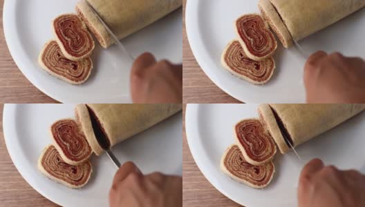在切罗洛之火。将巴西甜点Bolo de Rolo(瑞士卷，卷饼)切成薄片，放在白色的盘子上，以木材为背景高清在线视频素材下载