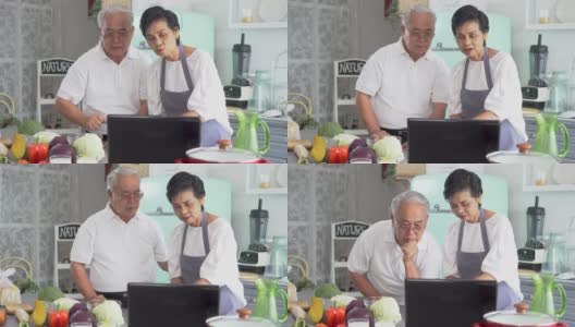一对亚洲老年夫妇在家做饭时使用笔记本电脑。70年代老年男女关系退休生活方式概念高清在线视频素材下载