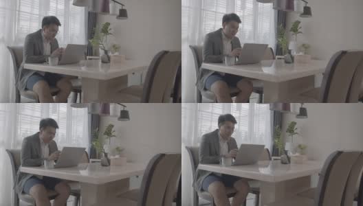 亚洲男人在家工作，在家里餐桌上的临时办公室高清在线视频素材下载