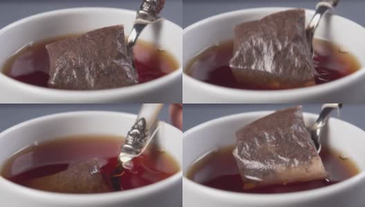 将茶匙和茶包浸在热水中，然后在一个白色的杯子里泡茶高清在线视频素材下载