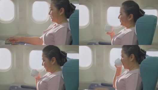 亚洲资深商务女性乘客在飞机上独自坐在商务舱感觉放松，享受和快乐喝一杯咖啡。旅游旅游度假或假日概念。高清在线视频素材下载