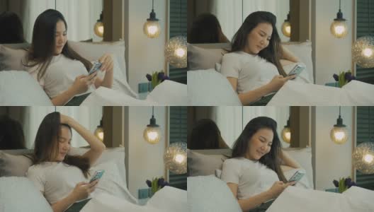 亚洲女性早上躺在床上用智能手机查看社交应用。高清在线视频素材下载