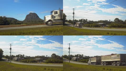 Semi-truck drives past a farm by a Mountain高清在线视频素材下载