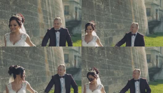 一对可爱的新婚夫妇在古老的城堡附近跑步高清在线视频素材下载
