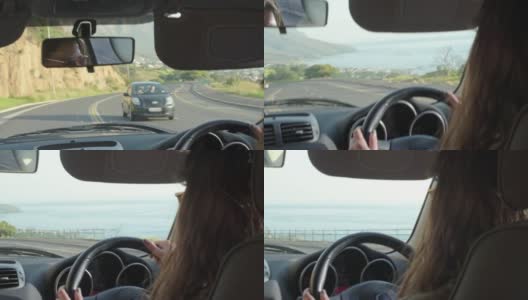一个年轻的女人开着车沿着海边一条风景优美的道路行驶高清在线视频素材下载