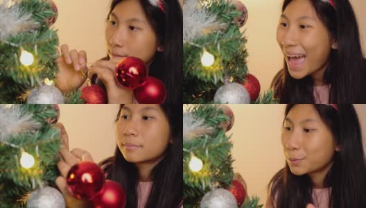 快乐的亚洲女孩戴着驯鹿发带，晚上在家装饰圣诞树，庆祝节日的概念。高清在线视频素材下载