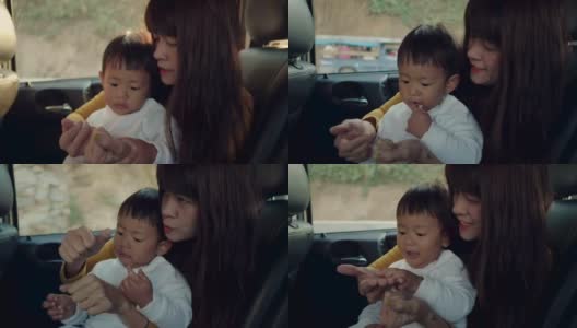 年轻的亚洲母亲带着男婴开车旅行。高清在线视频素材下载