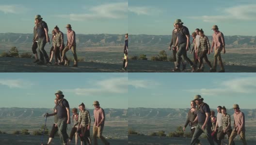 一群三十多岁的人一起徒步行走在科罗拉多大路口的科罗拉多国家纪念碑的沙漠里，俯瞰日落时分的书克利夫高清在线视频素材下载