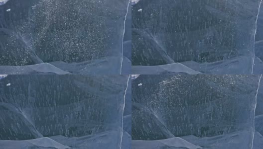 雪在冰面上飞舞。雪花在贝加尔湖的冰面上飞舞。冰非常美丽，有独特的裂缝。雪花闪耀着红光。在日落时分。高对比度。高清在线视频素材下载