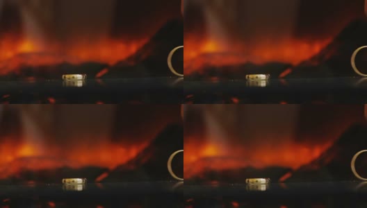 金色的戒指在壁炉火的背景上黑黑的一个滚动到另一个高清在线视频素材下载