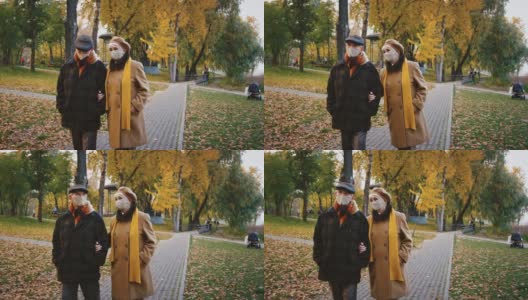 老年配偶，戴着防护口罩的祖父母在秋季城市公园散步时交谈，冠状病毒大流行高清在线视频素材下载