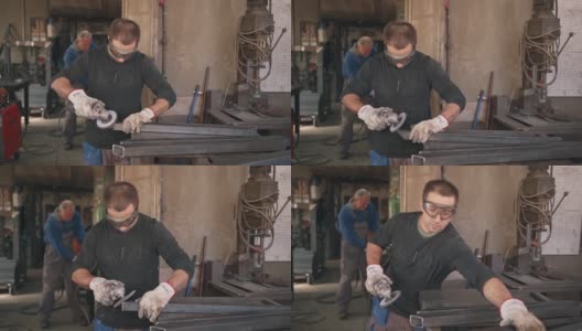 中年的专业焊工在他的焊接车间里打磨一根金属棒高清在线视频素材下载