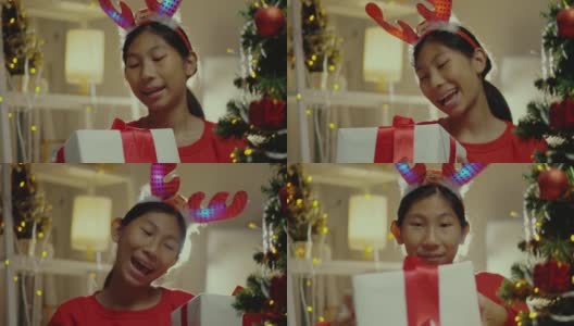 快乐亚洲女孩穿着红毛衣摇礼盒后收到来自家人用圣诞装饰在家里的生活理念。高清在线视频素材下载