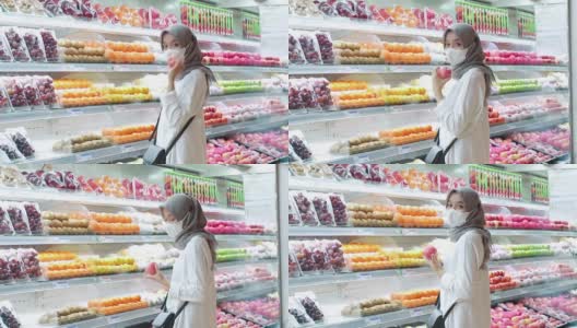 亚洲年轻女子戴着口罩在超市买水果高清在线视频素材下载