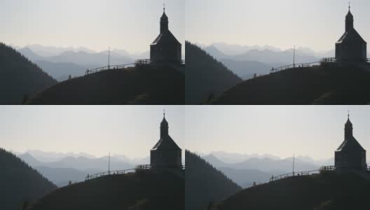 2019年10月23日，德国泰根塞:位于巴伐利亚阿尔卑斯山脉风景如画的山坡上的一座老教堂，游客们在教堂附近漫步高清在线视频素材下载