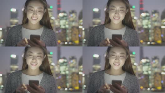 年轻的亚洲妇女在现代城市玩手机高清在线视频素材下载