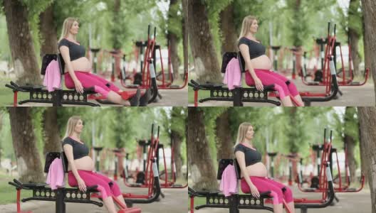 一位孕妇在户外骑着健身自行车训练高清在线视频素材下载