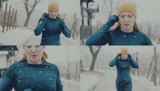 一名女子在雪地里慢跑前，将耳塞式耳机戴在耳朵上高清在线视频素材下载