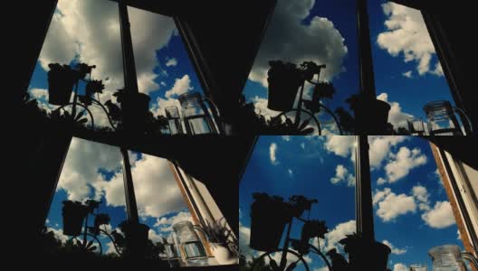在一个阳光明媚的夏天，从一间窗台上有花的房子的窗口看到了蓝天的时间流逝。高清在线视频素材下载