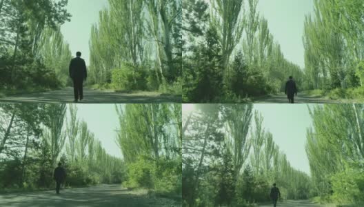 后视镜:西装革履的人独自穿过森林或花园的树木。孤独的男孩走在林间的小径或人行道上，林间有高大的绿树。缓慢的运动。无人机高清在线视频素材下载