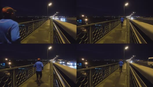 晚上在桥边慢跑的运动员。一个穿着运动服的男人在晚上跑步。男正在健身，车路过。高清在线视频素材下载