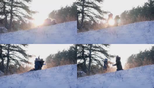 快乐的冬天休息，妈妈和儿子在雪地上背光玩在森林背景美丽的自然高清在线视频素材下载