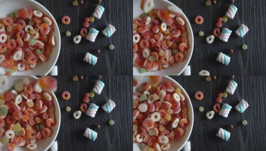 在木制背景上，多色糖果倒入碗中的慢动作高清在线视频素材下载