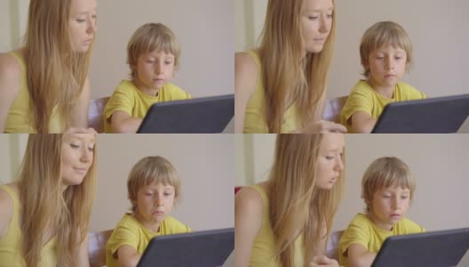 一位年轻妇女和她的小儿子在隔离期间坐在家里，在互联网学校使用平板电脑学习。冠状病毒的概念高清在线视频素材下载