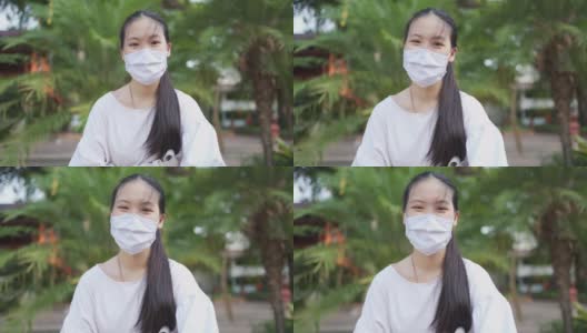 在新冠肺炎疫情中，身穿白布口罩的亚洲少女面带微笑高清在线视频素材下载