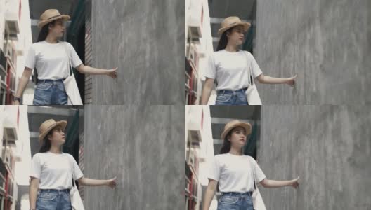 美丽的亚洲女人戴着一顶复古的帽子，拿着一个布袋，用手轻轻触摸着墙的背景，看着一条小街道享受着假期的夏天。高清在线视频素材下载