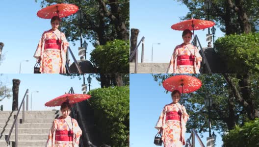 亚洲妇女穿着传统的日本和服，拿着红色的纸伞高清在线视频素材下载