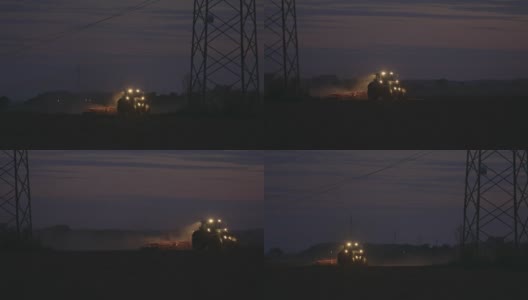 SLO MO拖拉机在夜间的电塔下犁地高清在线视频素材下载