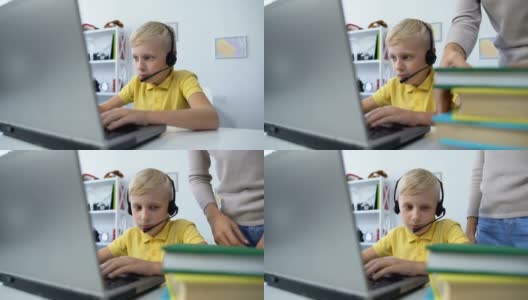 妈妈把书放在书桌上，儿子在耳机上玩电脑游戏上瘾高清在线视频素材下载
