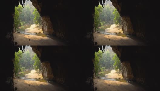 一个老妇人在一个大洞的底部收集蝙蝠粪，洞里有一条河。泰国Tham Lod Cave, Pai。高清在线视频素材下载
