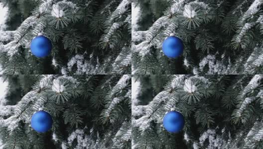 蓝色的圣诞球挂在云杉树枝和雪花高清在线视频素材下载