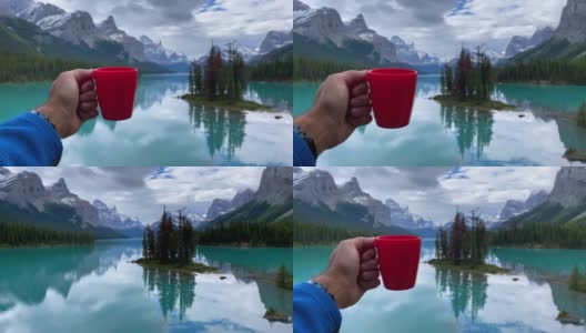 加拿大阿尔伯塔省贾斯帕国家公园，玛琳湖的精灵岛，一只展示咖啡杯的人手高清在线视频素材下载