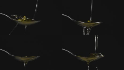 特写将橄榄油液体倒入勺子在黑色背景的慢动作高清在线视频素材下载