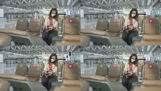 正面:只有亚洲女性穿着粉色t恤，戴着防护COVID-19的口罩，带着行李、护照、机票，在机场等待新的旅程、旅行、度假时使用智能手机、触摸社交媒体。高清在线视频素材下载