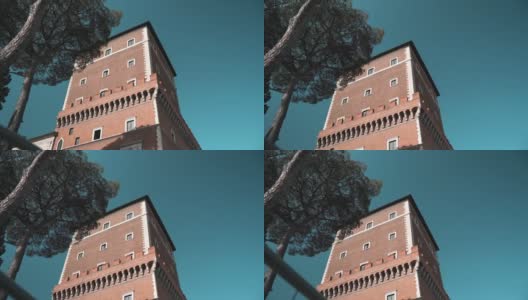 威尼斯宫著名塔在阳光下的低角度，惊人的蓝色狡猾的背景和生长的松树，罗马市中心特色罗马建筑立面的塔，意大利文化和建筑高清在线视频素材下载