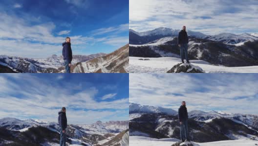 鸟瞰图，年轻的白种人胡子时尚的人站在一块大石头上，在风景如画的雪山覆盖的岩石。晴天，蓝天白云高清在线视频素材下载