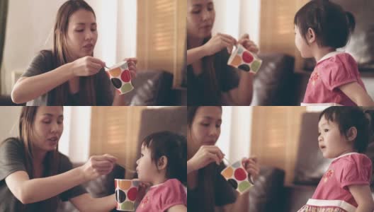 年轻的母亲用勺子喂女婴高清在线视频素材下载
