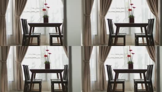 带花瓶的木桌模糊了帘窗与绿色花园，摄影车从右向左拍摄高清在线视频素材下载