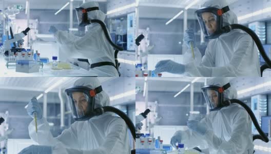 医学病毒学研究科学家工作在防护服与面具，她使用微型吸管。她在一个无菌的高科技实验室工作，研究设施。高清在线视频素材下载