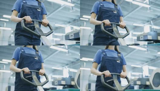 美丽的安全帽女工人操作托盘升降机在一个大的工厂大楼。高清在线视频素材下载