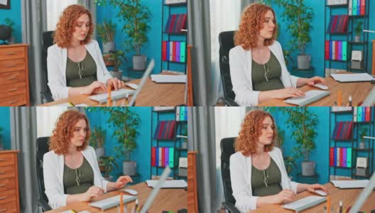 这位红头发、经验丰富的经理坐在办公室的办公桌前，对着电脑屏幕，检查电子邮件、信息、报告、填写文件、管理公司、安排日程高清在线视频素材下载