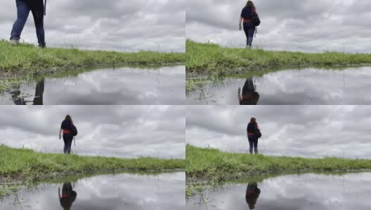 看风景。背影一个女人走过水，然后站在秋天的云彩前。系列的一部分。高清在线视频素材下载